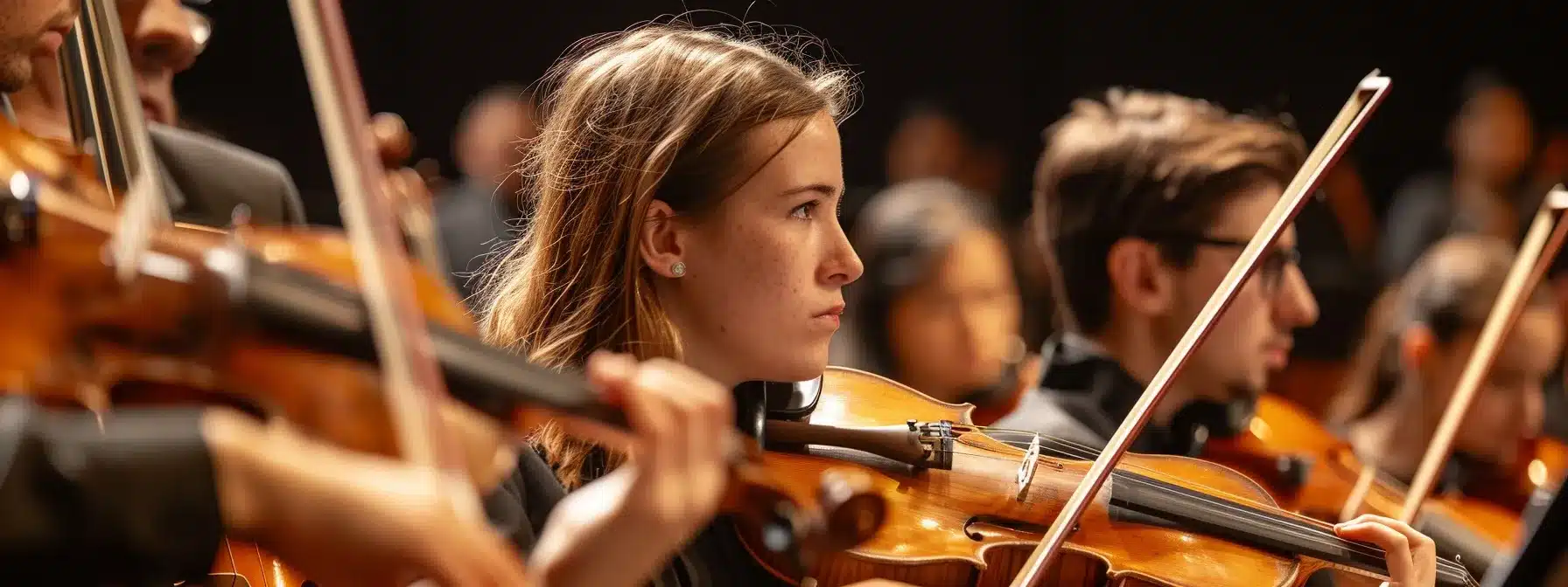 musicians in a community orchestra sitting attentively in their seats with their instruments ready for rehearsal