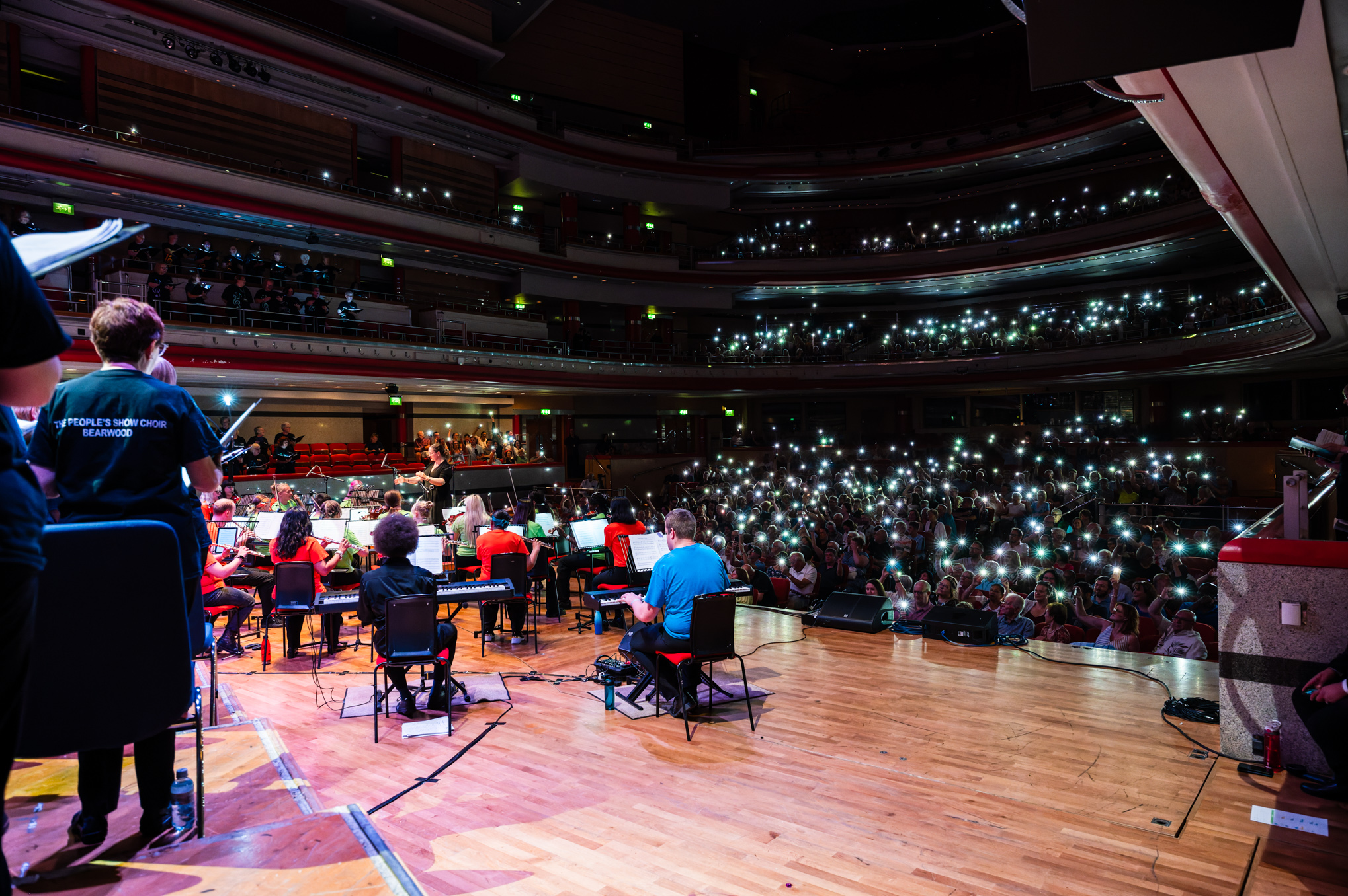 Performance of Love Shine a Light at Jukebox Live with phone torches shining at the stage.