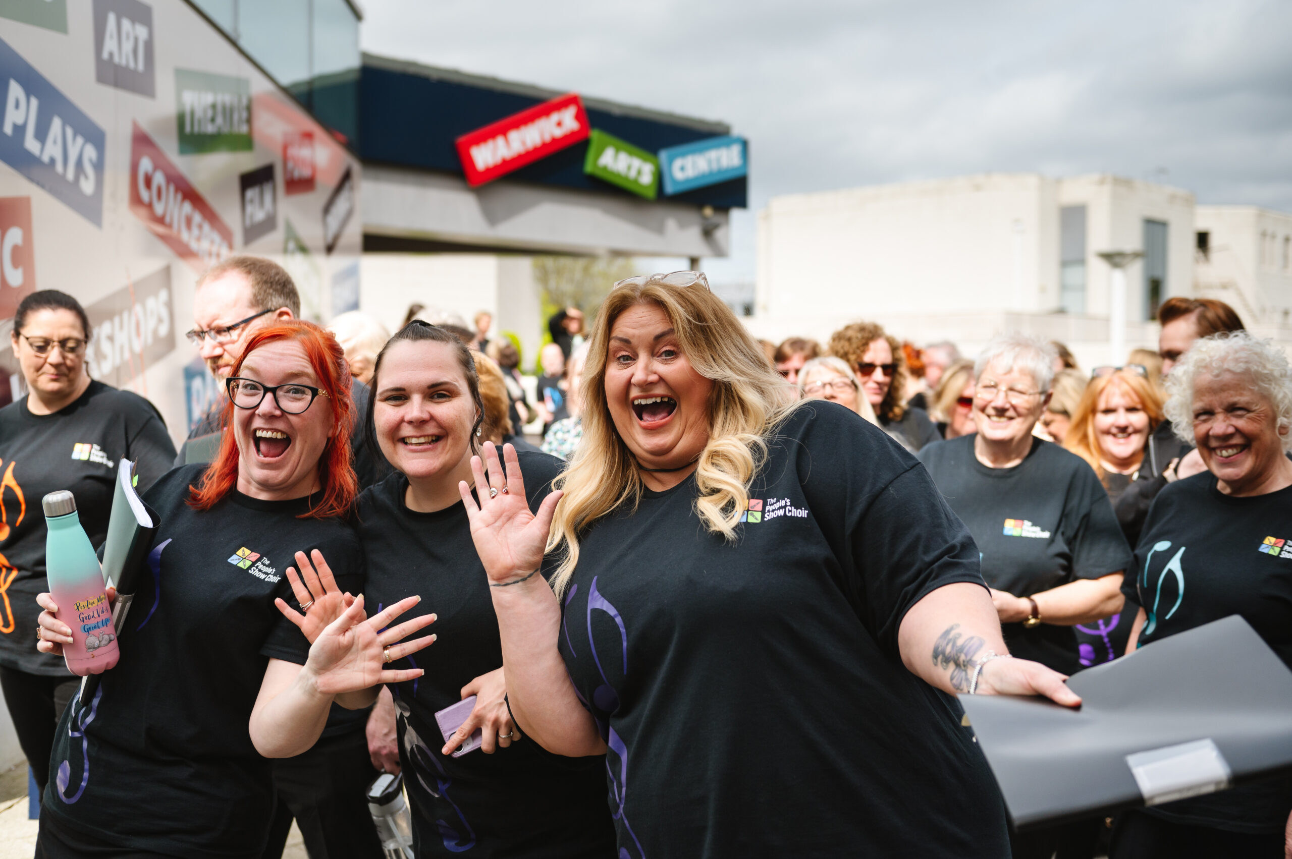 A female singer from West Bromwich TPSC dancing with her friends outside Warwick Arts Centre. 